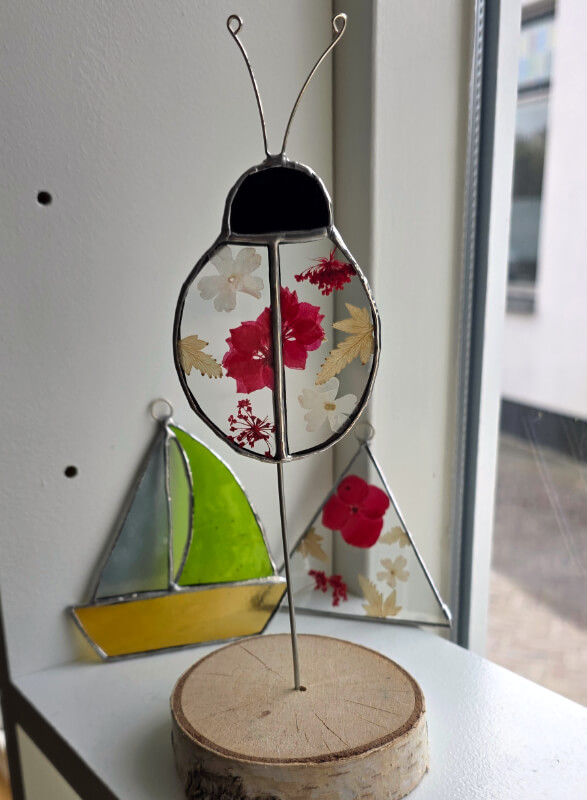 Studio dijkwater tiffany lieveheersbeestje droogbloemen 2 800px 72dpi Handgemaakte glaskunst lieveheersbeestje in Tiffany-techniek met droogbloemen tussen helder glas, zwart gepatineerd op houten voet, Studio Dijkwater Zeeland