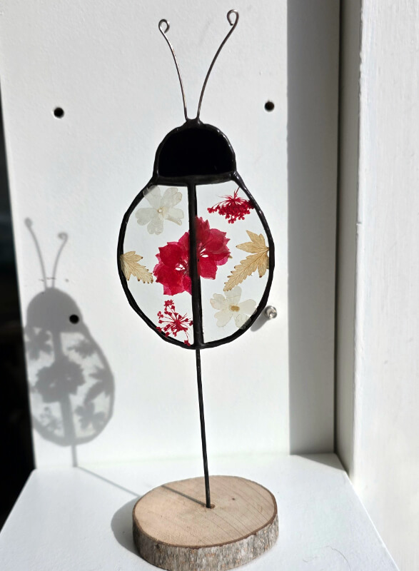 Studio dijkwater tiffany lieveheersbeestje droogbloemen 800px 72dpi Handgemaakte glaskunst lieveheersbeestje in Tiffany-techniek met droogbloemen tussen helder glas, zwart gepatineerd op houten voet, Studio Dijkwater Zeeland