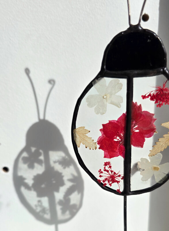 Studio dijkwater tiffany lieveheersbeestje droogbloemen weerspiegeling 800px 72dpi Handgemaakte glaskunst lieveheersbeestje in Tiffany-techniek met droogbloemen tussen helder glas, zwart gepatineerd op houten voet, Studio Dijkwater Zeeland